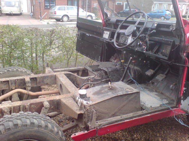 Red with the body removed, chassis exposed for welding work